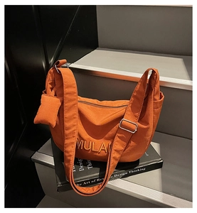 Detail view of pumpkin orange canvas crescent bag with embroidery and mini coin purse