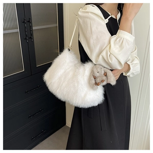 Détail d'un sac seau en fausse fourrure blanche avec pendentif lapin porté par un mannequin