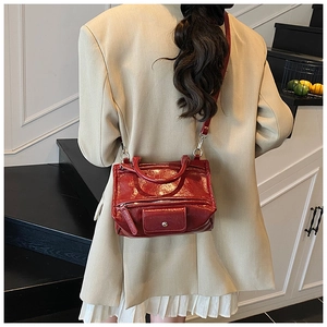Detail of burgundy patent leather handbag showing the stylish retro design and shoulder strap