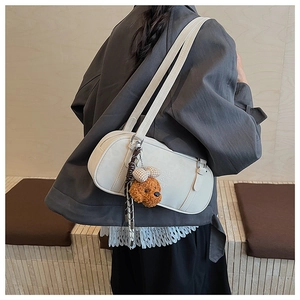 Detail of cream baguette bag with teddy charm and silk scarf worn by a model