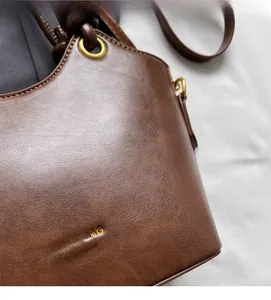 Detail der dunkelbraunen Lederhandtasche mit feiner Narbung und goldener Logoprägung