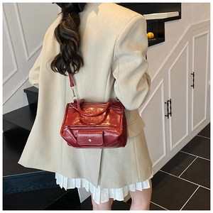 Detail of red glossy patent leather tote with dual handles and detachable shoulder strap