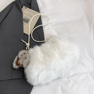 Détail d'un sac seau en fausse fourrure blanche avec une jolie peluche de lapin gris