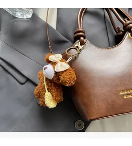 Nahaufnahme eines braunen Teddybär-Plüsch-Anhängers mit gelber Schleife an einer Tasche