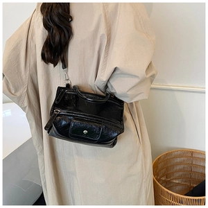 Detail of black glossy crossbody bag with褶皱 texture on stylish trench coat