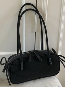 Minimalist matte black Boston shoulder bag with dual cylindrical straps and top zipper