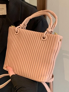 Pink pleated bucket bag with twisted handle and gold hardware in minimalist retro style