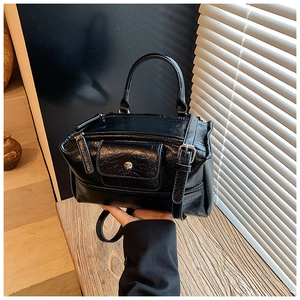 Detail of glossy black handbag showing wrinkled texture and adjustable shoulder strap