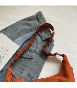 Detail view of the adjustable wide shoulder strap with metal buckle on the orange bag