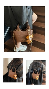 Detail der dunkelbraunen Lederhandtasche mit Goldbranding und Plüschbär-Anhänger Zubehör