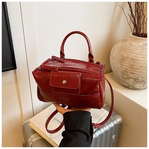 Close-up of vintage dark red leather handbag featuring metallic snap and removable strap