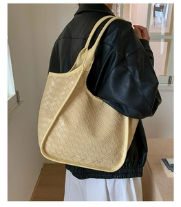 Vista dettagliata della grande borsa tote intrecciata color crema con tracolla ampia