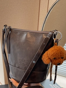 Vintage dark brown bucket bag with a cute plush dog pendant and leather texture