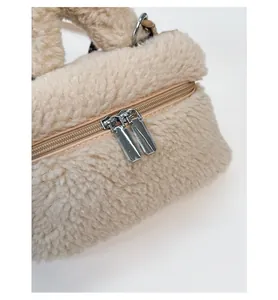 Dettaglio delle doppie cerniere in metallo e morbida texture in peluche beige della borsa