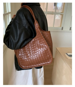 Borsa tote in pelle intrecciata marrone indossata a spalla da una modella per look casual