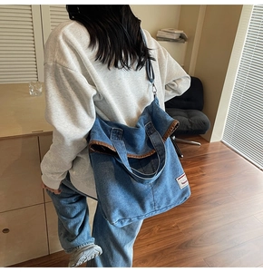 Close-up of denim tote bag with leather piping detail and adjustable shoulder strap