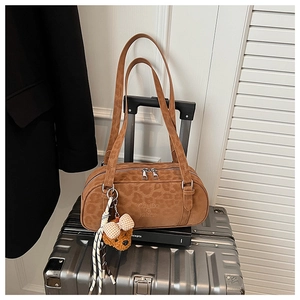 Detail of vintage leopard print suede handbag with plush bear charm on a silver suitcase