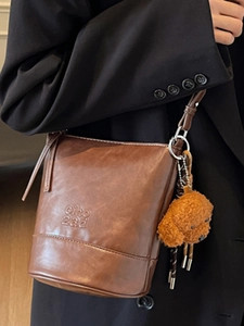 Vintage brown leather bucket bag for women with cute teddy charm on shoulder strap