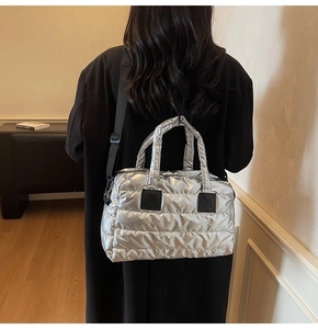 Détail du sac fourre-tout argenté matelassé avec poignées et bandoulière noire