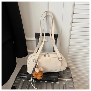 Close-up of cream faux suede bag on silver suitcase with a cute plush bear charm