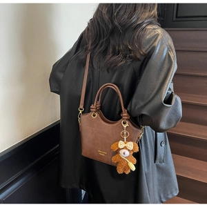 Schicke braune Kunstleder-Handtasche mit verstellbarem Gurt und süßem Plüschbär-Anhänger