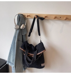 Detail of grey washed denim tote bag showing brown edge trim and adjustable strap