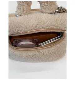 Dettaglio della capienza interna della borsa in peluche beige con trucco e cellulare