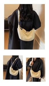 Detail view of the beige canvas crescent bag with white MULAIDI embroidery and strap