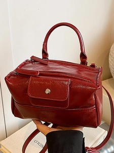 Deep red vintage leather handbag with top handle and metal buckle in a lifestyle setting
