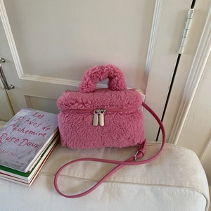 Dettaglio di una borsa in peluche rosa con manico superiore e tracolla in pelle fine