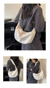 Detailed view of white canvas crescent bag with brand embroidery and small charm