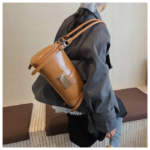 Caramel brown vintage cylinder shoulder bag worn by model in a minimalist setting