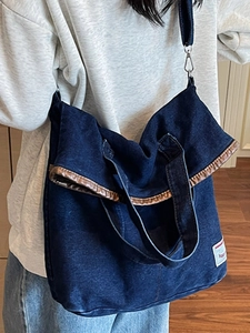 Large dark blue denim tote bag with leather trim and adjustable crossbody strap