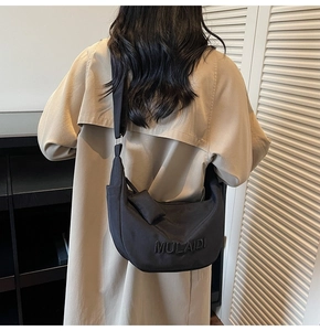 Close-up of black nylon crescent bag with MULAIDI embossed logo and mini pouch pendant