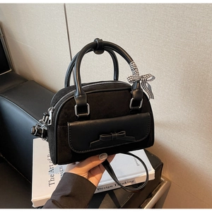 Détails d'un sac Boston noir avec poche à nœud et ruban décoratif à carreaux élégant