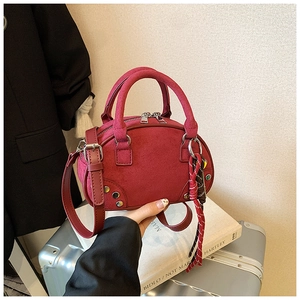 Close-up of burgundy suede Boston bag with silver studs and braided rope keychain detail