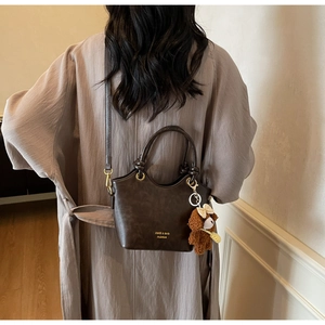Details der braunen Vintage-Ledertasche mit goldenen Beschlägen und Bärenanhänger