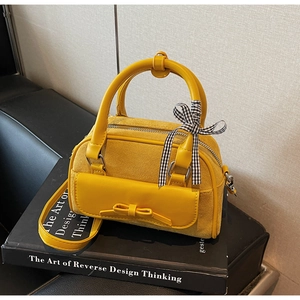 Détail du sac Boston jaune en daim avec poche à nœud et ruban décoratif à carreaux