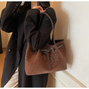 Detailed view of brown leopard print tote bag with buckle straps on model's shoulder