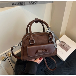 Détail du sac Boston en daim marron avec rabat à nœud élégant et ruban en soie décoratif
