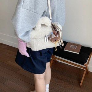Vista dettagliata della borsa in peluche beige con un simpatico ciondolo a orsetto