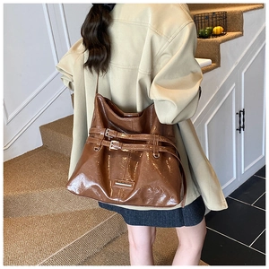 Detail of brown glossy leather tote bag with stylish buckle straps on staircase