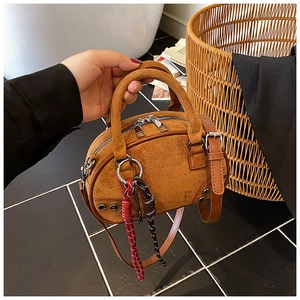 Detail view of brown suede mini pillow bag with silver rivets and colorful woven charm