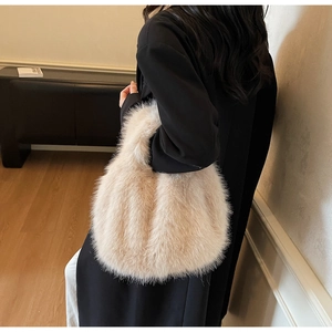 Détail d'un sac à main en fausse fourrure beige porté avec un manteau d'hiver noir