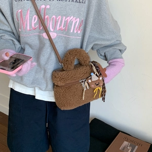 Dettaglio borsa di peluche marrone con ciondolo a forma di orso e tracolla intrecciata