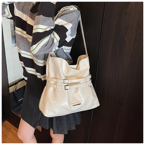 Close-up of cream glossy tote bag with buckle details and spacious interior for daily use