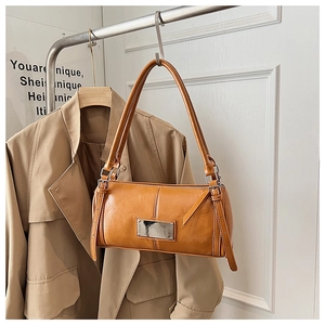 Close-up of caramel cylindrical bag with polished metal plate and adjustable strap