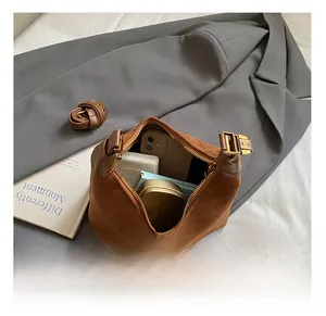 Interior view of brown suede bucket bag with phone and makeup kit on a grey blazer background