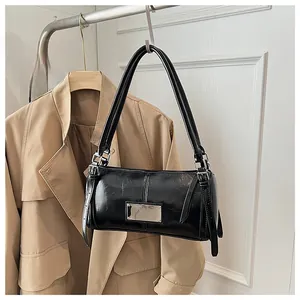 Detail of black patent leather cylinder bag with silver hardware and glossy finish