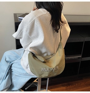 Detailed back view of an olive green crescent canvas bag with embroidered MULAIDI letters